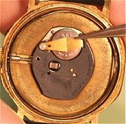 Watch battery retained by a screw clip watch